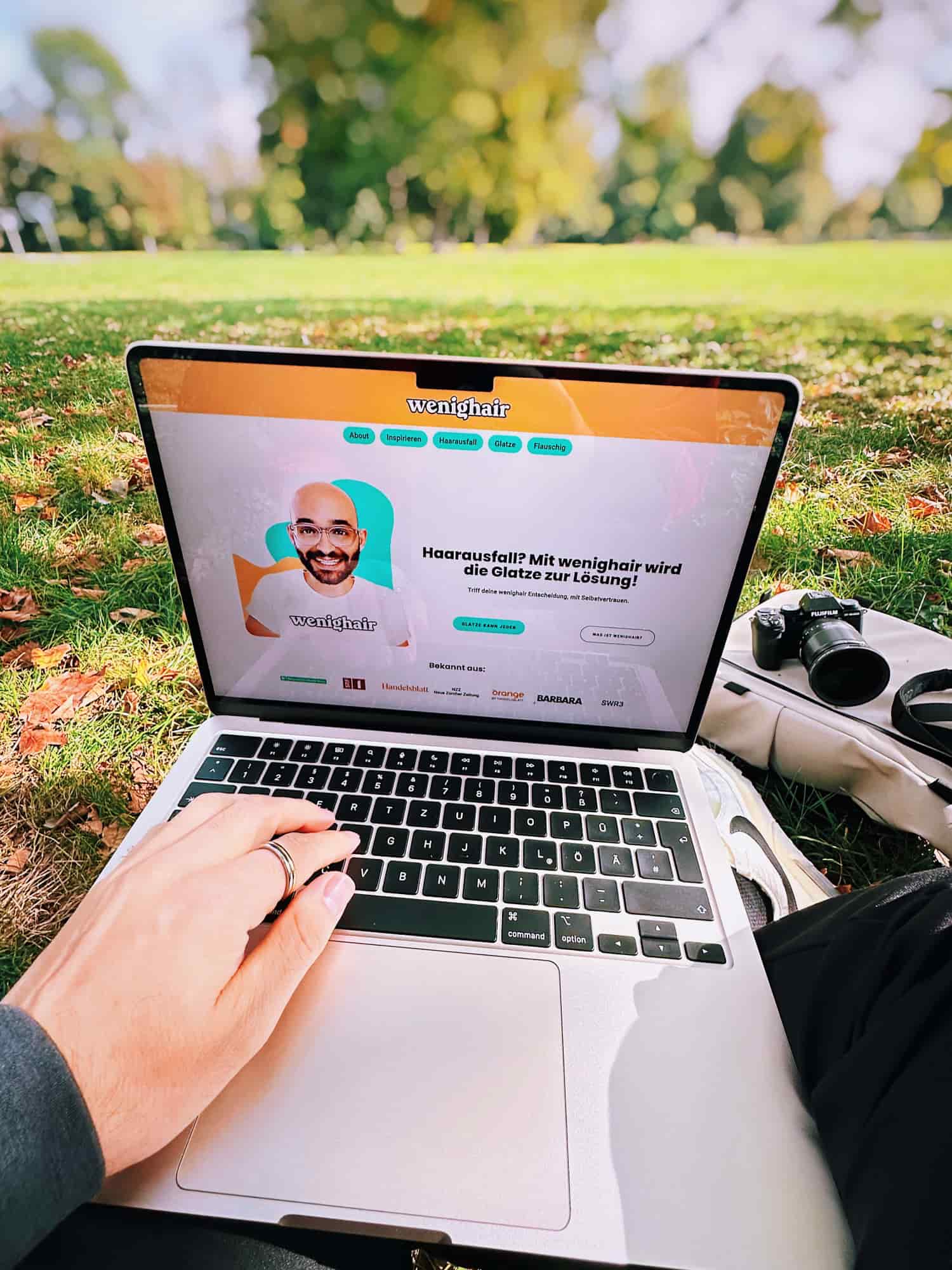 Arbeiten im Park mit Laptop, zeigt die Website wenighair für Haarverlust, kreative Outdoor-Arbeitsweise eines UX Designers