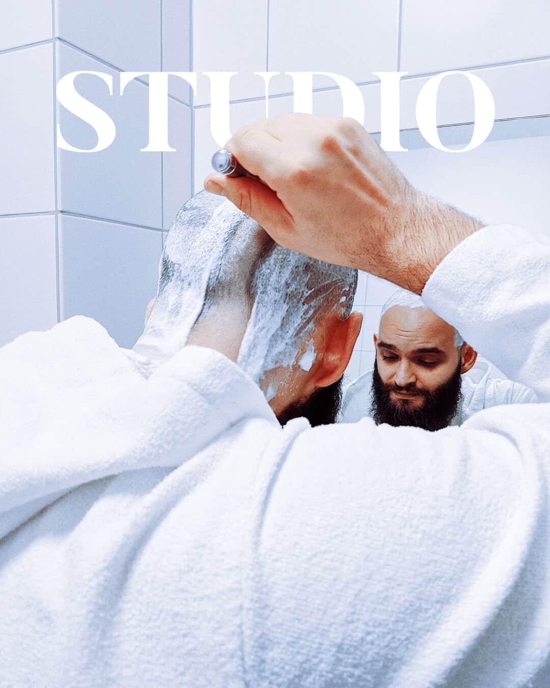 Mann rasiert sich den Kopf im Badezimmer. "STUDIO" Overlay symbolisiert Selbstpflege als Teil der kreativen Arbeit.